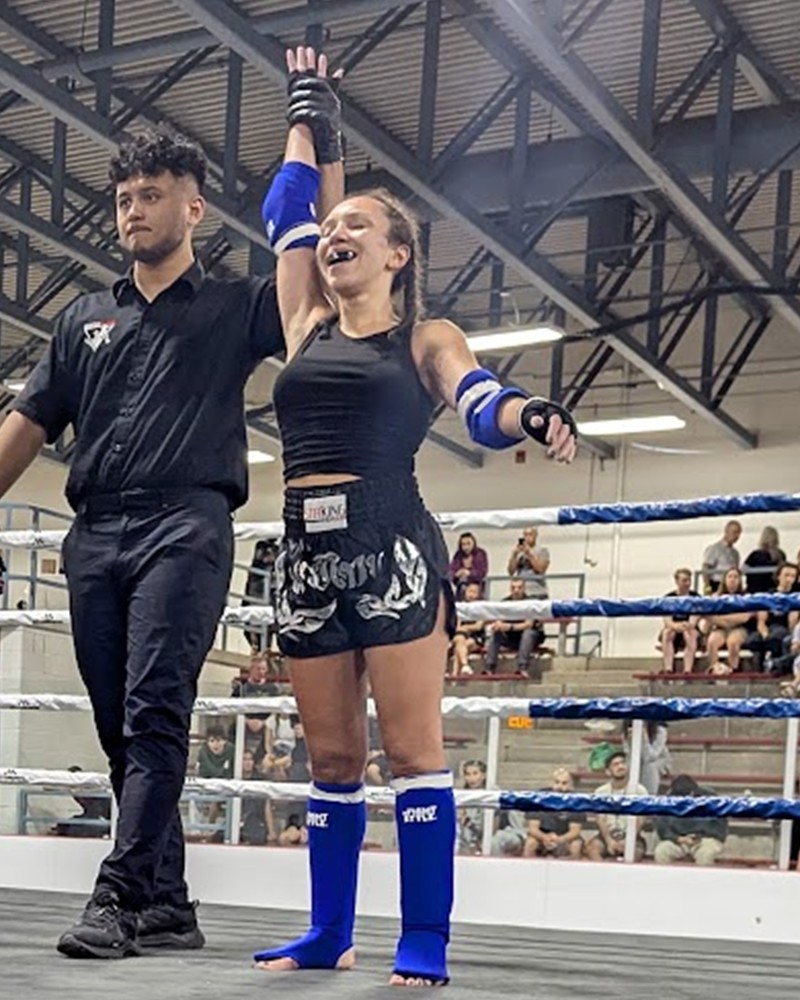 Lani Rosenbaum centered with her hand raised after a Muay Thai victory